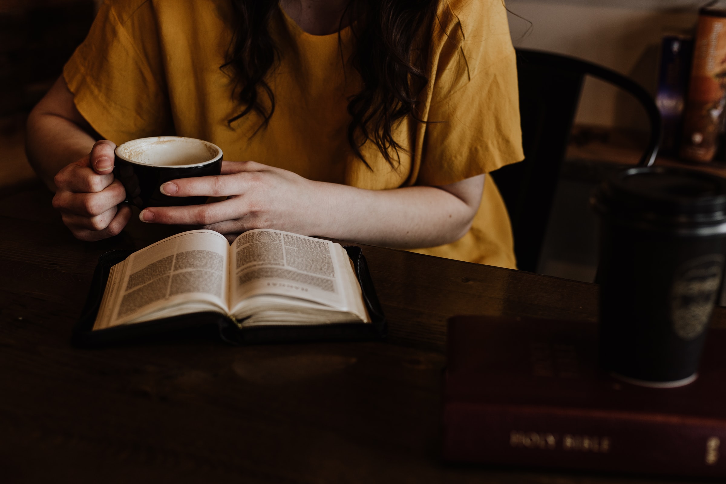 woman reading book whilst drinking coffee